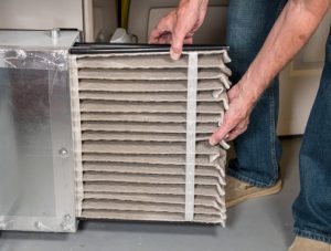 person-pulling-an-air-filter-out-of-a-furnace